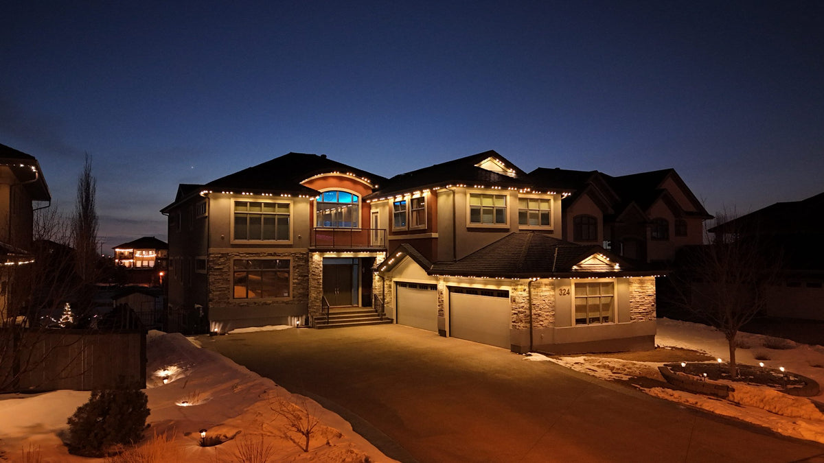 Drone view of a permanent lighting install along the roofline and garage