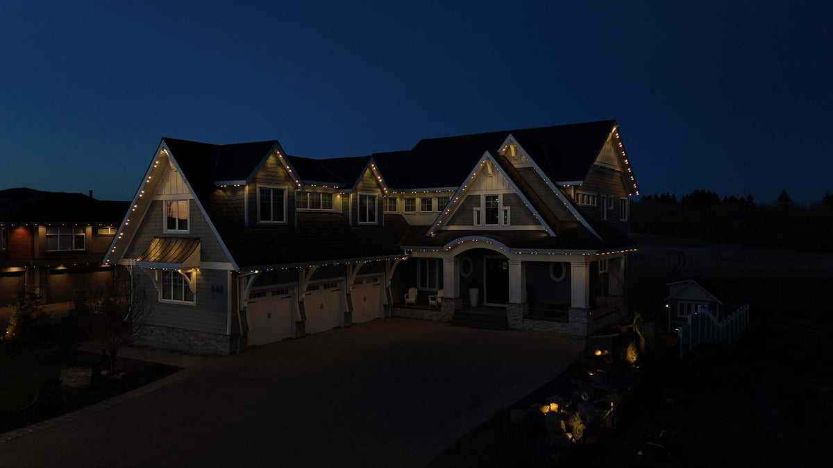 Large home with permanent lights tracing every gable at night